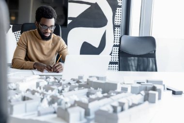 Yoğun bir gün. Ofiste çalışan ve meşgul görünen Afrikalı Amerikalı genç bir adam.