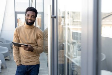 İnternette. Elinde tabletle dışarıda bekleyen Afro-Amerikan bir adam.