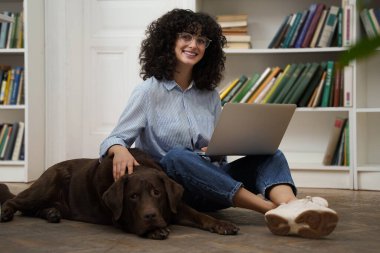 Bir arkadaşla. Dizüstü bilgisayarda çalışan ve yanında yatan köpeğini okşayan hoş bir kadın.