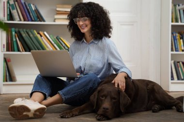 Bir arkadaşla. Dizüstü bilgisayarda çalışan ve yanında yatan köpeğini okşayan hoş bir kadın.