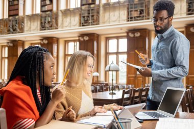 Tartışma. Bir grup genç kütüphanede bir şey tartışıyor.