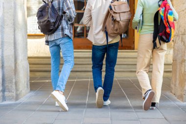 Bir grup öğrenci üniversite derslerinden sonra kameraya doğru geri geri yürüyor.