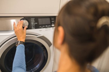 Ev temizliği. Ev hanımı çamaşır makinesi hazırlıyor.
