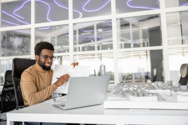 Çevrimiçi öğretim. Mimar, projesini çevrimiçi bir derste gösteriyor ve memnun görünüyor