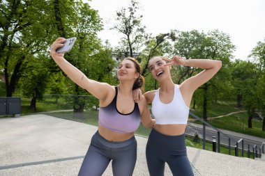 Spor kıyafetleri içinde atletik çekici kadınlar spor yaparken selfie çekiyorlar.