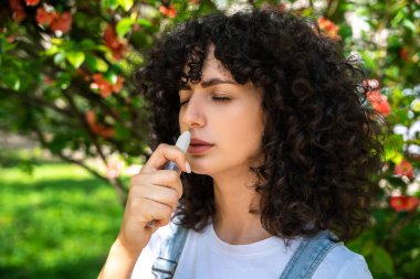 Burun spreyi. Siyah saçlı genç kadın alerji belirtileri gösterirken burun spreyi kullanıyor.