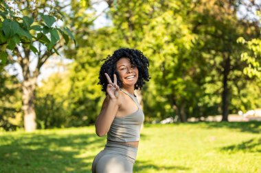 Temiz havada egzersiz yapmak. Parktaki güzel kıvırcık saçlı kadın antrenman yapıyor ve mutlu görünüyor.