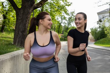 Spor hocasıyla stadyumda koşarken kilolarını veren etkin, iri yarı bir kadın.
