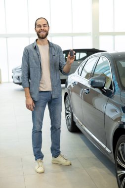 Yeni araba. Arabanın yanında rahat giysiler içinde kendinden emin genç bir adam var.