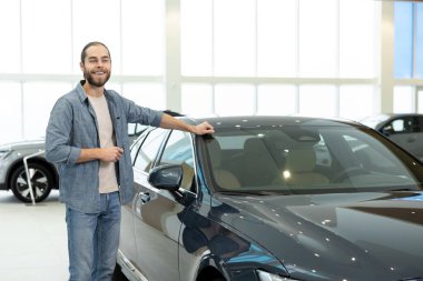 Yeni araba. Arabanın yanında rahat giysiler içinde kendinden emin genç bir adam var.