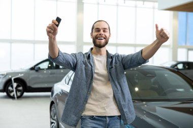 Yeni araba. Araba kuaföründe elinde araba anahtarlarıyla heyecanlı bir genç adam.