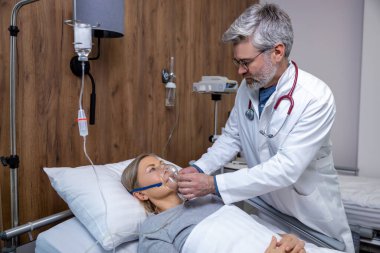 Oksijen maskesi. Doktor kadın bir hastaya oksijen maskesi takıyor.