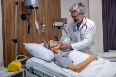 Yoğun terapi. Yoğun terapi bölümünde çalışan ve hastaya oksijen maskesi takan bir doktor.