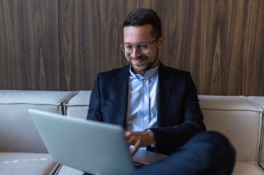 Gözlüklü başarılı iş adamı ofis içi dizüstü bilgisayarda çalışıyor.