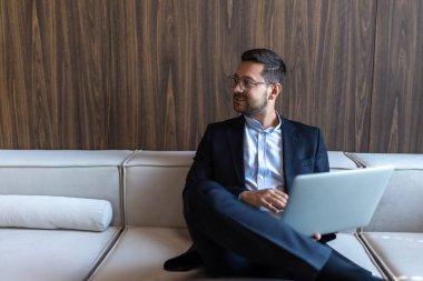 Gözlüklü başarılı iş adamı ofis içi dizüstü bilgisayarda çalışıyor.