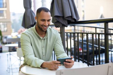 Genç ve başarılı bir siyahi adam açık havada internet uygulaması kullanarak şehirde telefonla dolaşıyor..