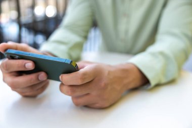 Açık havada video oyunları oynayan ve cep telefonu kullanan tanınmayan bir adamın yakınlaşması