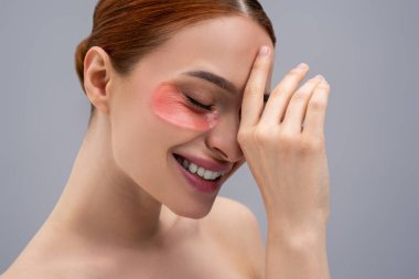 Göz bölgesi bakımı. Gözlerinin altında nemlendirici bantları olan güzel bir genç kadının portresi.