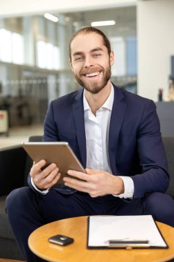 Araba galerisinde dijital tablet üzerinde çalışan yakışıklı gülümseyen adam.