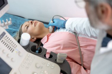 Ultrasonografi. Doktor kadın bir hastaya tiroid bezi ultrasonografisi yapıyor.