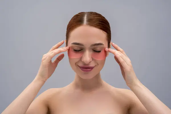 stock image Face care. Cute young woman using beauty patches under her eyes and looking contented