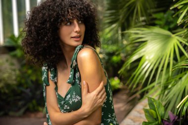 Sevimli siyah saçlı kadın model egzotik yeşilliklere karşı duruyor.
