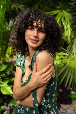 Sevimli siyah saçlı kadın model egzotik yeşilliklere karşı duruyor.