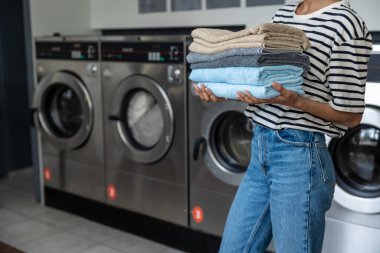 Kamu çamaşırhanesinde havlu taşıyan tanınmayan isimsiz bir kadın.