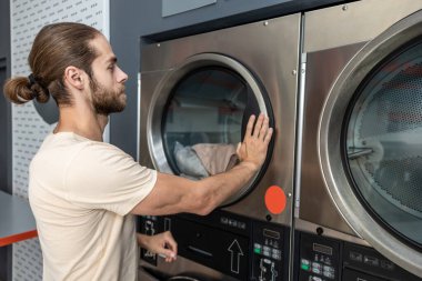 Çalışkan bir adam sanayi çamaşırhanesinde çamaşır yıkıyor.