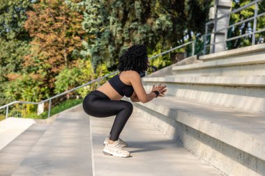 Antrenman yapıyorum. Kadın dışarıda egzersiz yapıyor ve konsantre ve odaklanmış görünüyor.