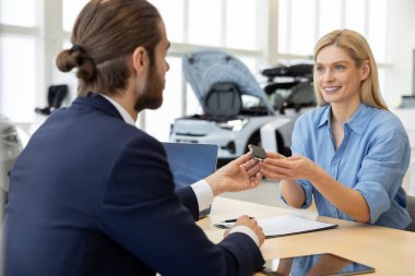 Sakallı satıcı, krupiye ofisinde kadın müşteriyle kredi sözleşmesi imzalıyor.