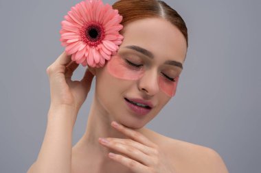 Çiçek desenli genç bir kadın. Gri arka planda yalıtılmış cilt bandı kullanıyor.