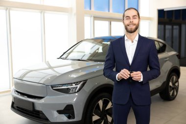 Araç galerisinde çalışan sakallı adam resmi giysiler giyiyor. Araba galerisinde çalışıyor.