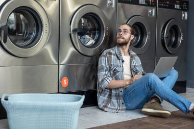 Kafkasyalı serbest çalışan ticari çamaşırhanede beklerken bilgisayardaki işleri tamamlıyor.