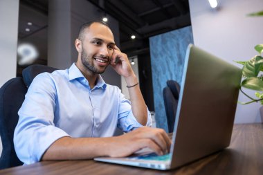 İşadamı iş yerinde otururken bilgisayarda çalışıyor.