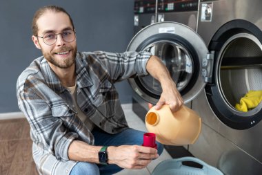 Çamaşırhanedeki çamaşırları yıkayan sakallı adam.