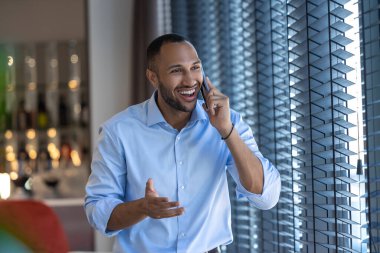 Pencerenin yanındaki genç siyahi adam kafenin içinde akıllı telefondan konuşuyor.