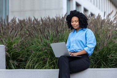 Çalışıyorum. Laptoplu esmer kadın bankta oturuyor ve çalışıyor.