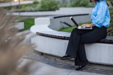 İş günü. Dizüstü bilgisayarla çalışan mavi gömlekli kadını kapat.
