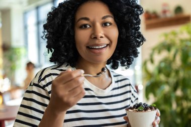 Lezzetli tatlı. Çizgili bluzlu kadın lezzetli tiramisunun tadını çıkarıyor.