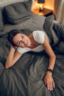 Evde sabahlar. Koyu renk saçlı kadın sabah yatak odasında kendini rahat hissediyordu.