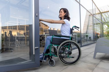 Ofise giriyorum. Ofis girişinde tekerlekli sandalyedeki siyah saçlı kadın.