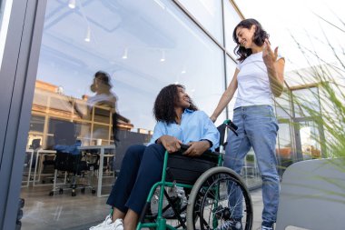 Arkadaşız. Engelli bir Afrikalı Amerikalı kadınla tekerlekli sandalye taşıyan genç bir kadın.