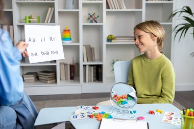 Konuşma dersi için. Sarışın çocuk, kadın bir konuşma terapistiyle konuşma dersi veriyor.