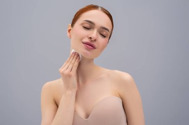 Yüz temizleme. Yüzünü süngerle temizleyen tatlı bir genç kadın.