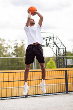 İyi atıştı. Erkek basketbolcu topu potaya atıyor.