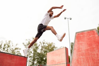 Atlıyorum. Spor giyimli bir adam bir sokaktan diğerine zıplıyor.