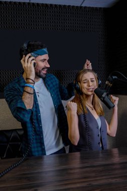 Hippi erkek ve kadın playback şarkıcıları stüdyoda kayıt yapıyor.