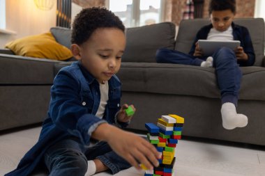 Çocuk evde dijital tablet ve renkli yapı bloklarıyla oyun oynuyor