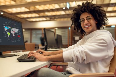 Young man student browsing educational software on his computer in university library clipart